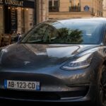 Voiture Tesla avec plaque d'immatriculation française homologuée dans une rue de Paris.